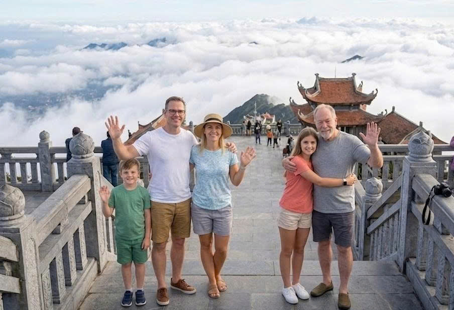 A family celebrating at the peak of Fansipan mountain, surrounded by beautiful clouds and traditional temple architecture.