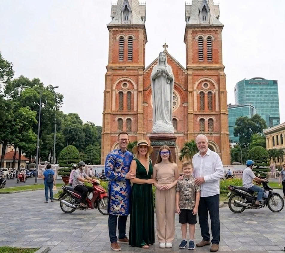 A family posing in front of the historic Notre Dame Cathedral in Ho Chi Minh City, Vietnam.