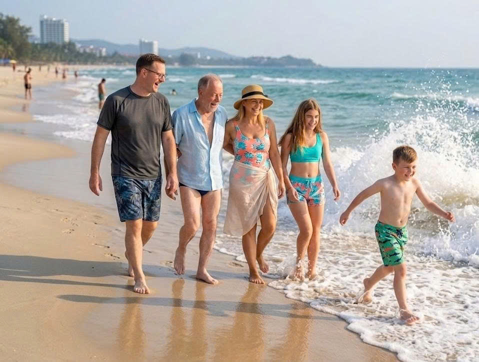 A happy family walking along the sandy beach with ocean waves splashing during their vacation in Vietnam.
